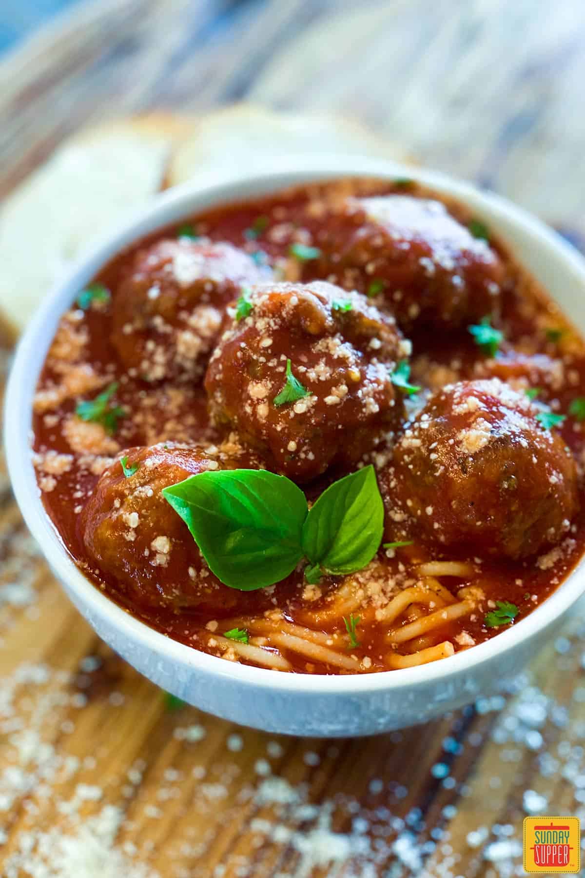 Sauce for meatballs over meatballs and spaghetti in a white bowl