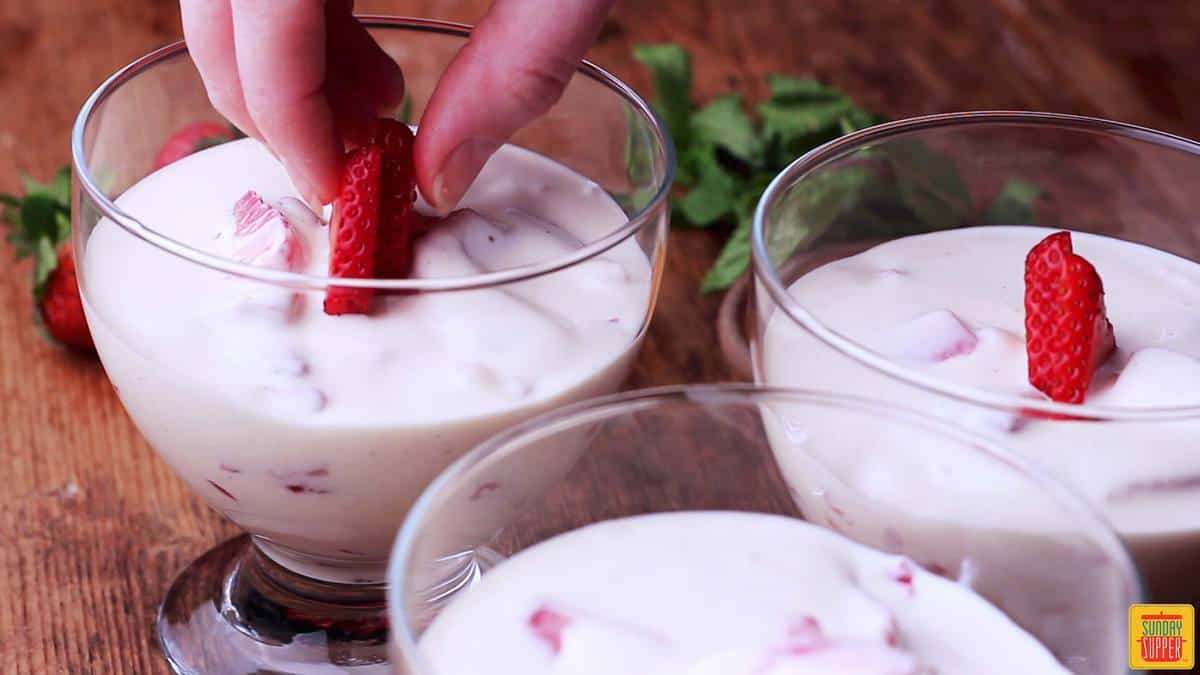 Adding fresh strawberries to Fresas con Crema recipe bowls