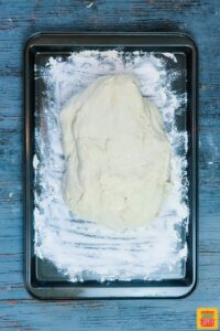 Dough for homemade french bread recipe on floured baking sheet
