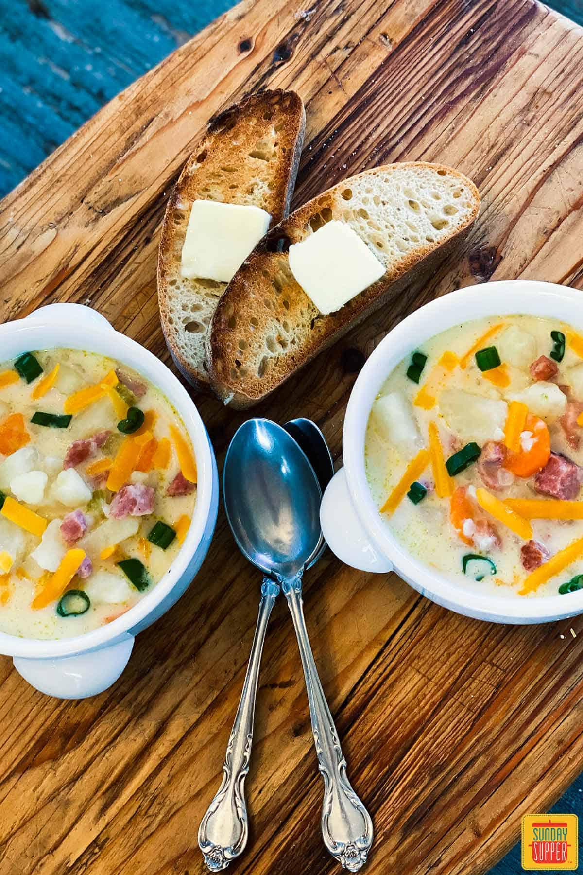 Two bowls of leftover ham soup with spoons and bread