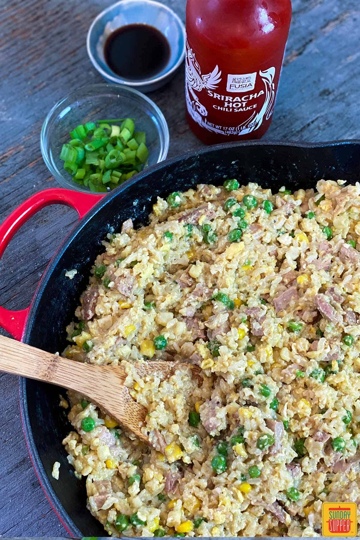 Fried rice and pork in the skillet with a wooden spoon