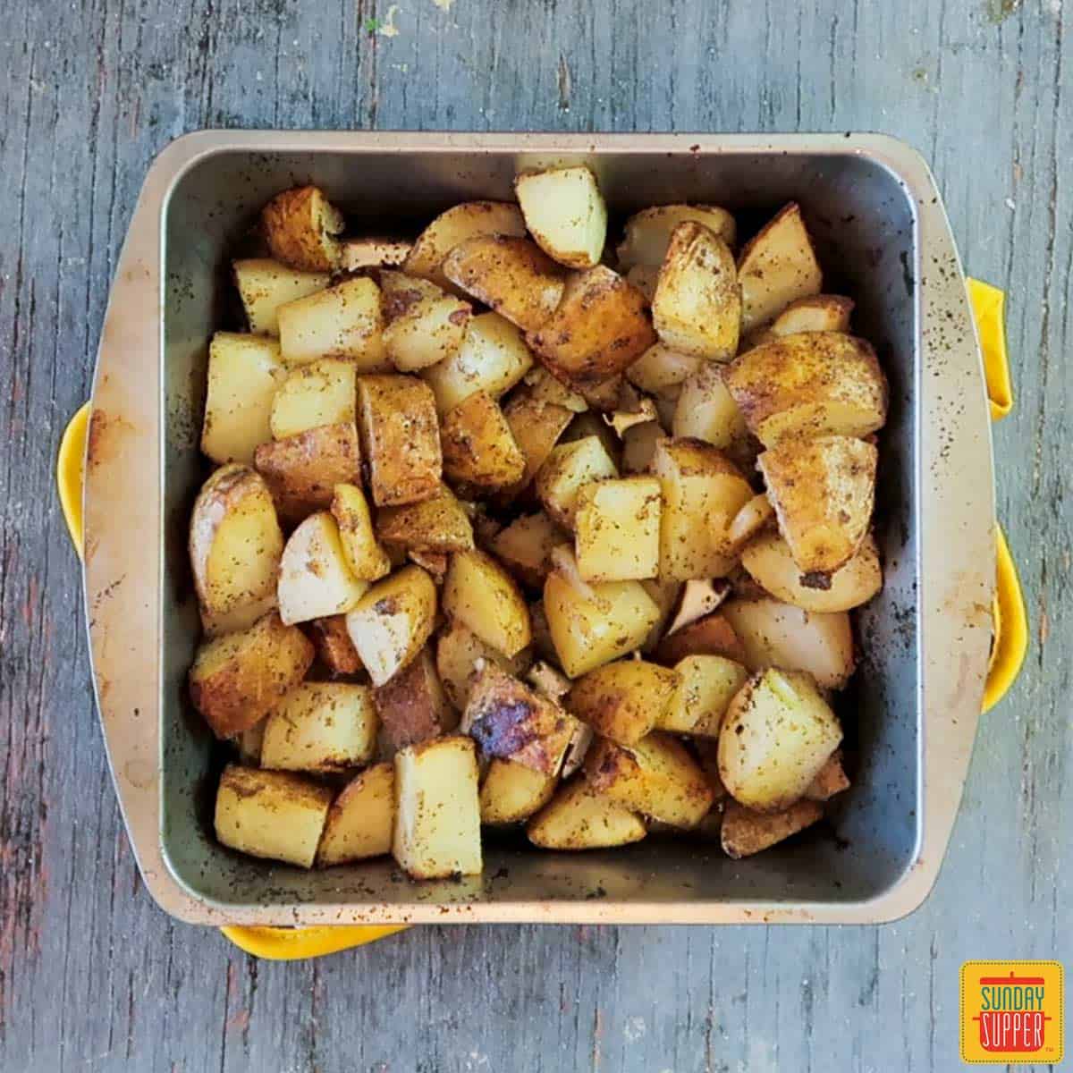 Grilled potatoes recipe fresh off the grill in the baking tin resting on an oven towel