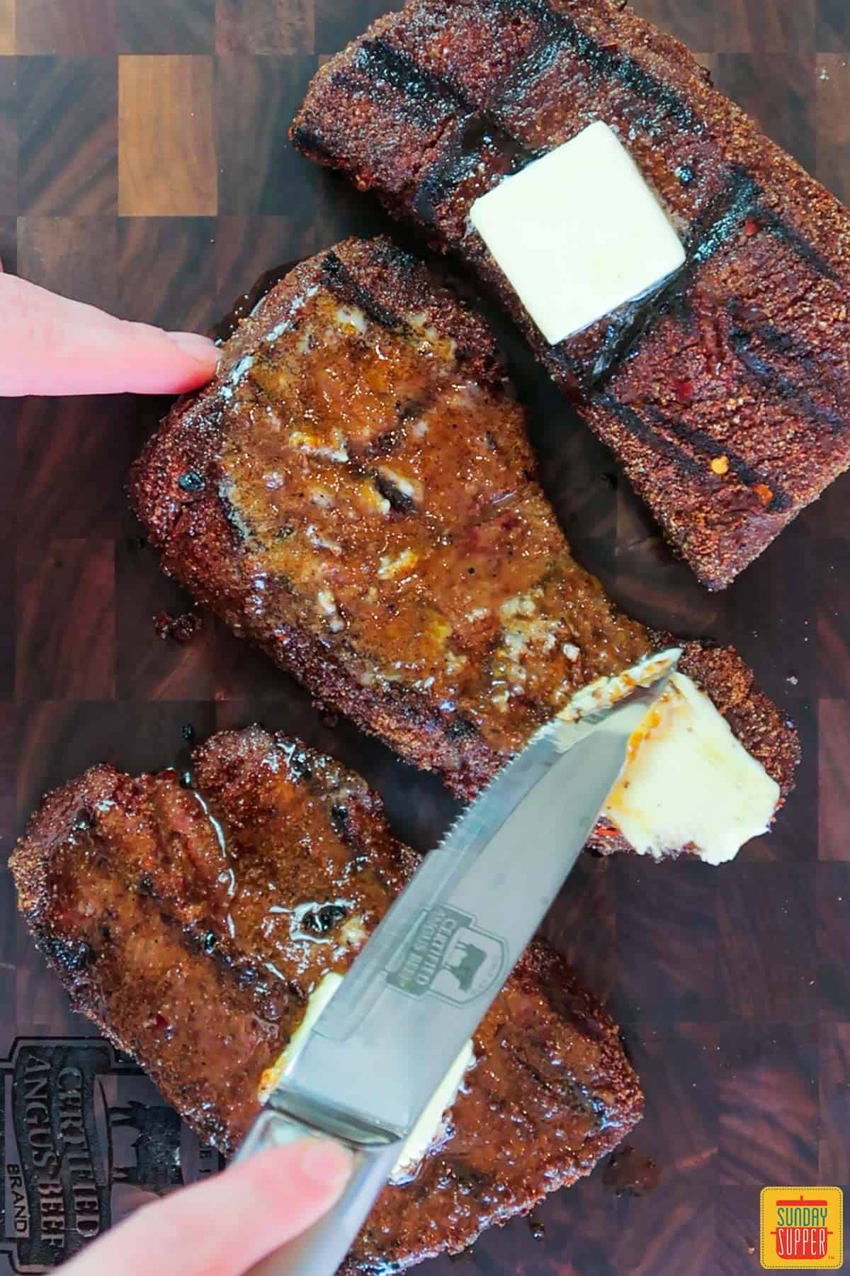 Spreading a pat of butter onto the cooked short ribs