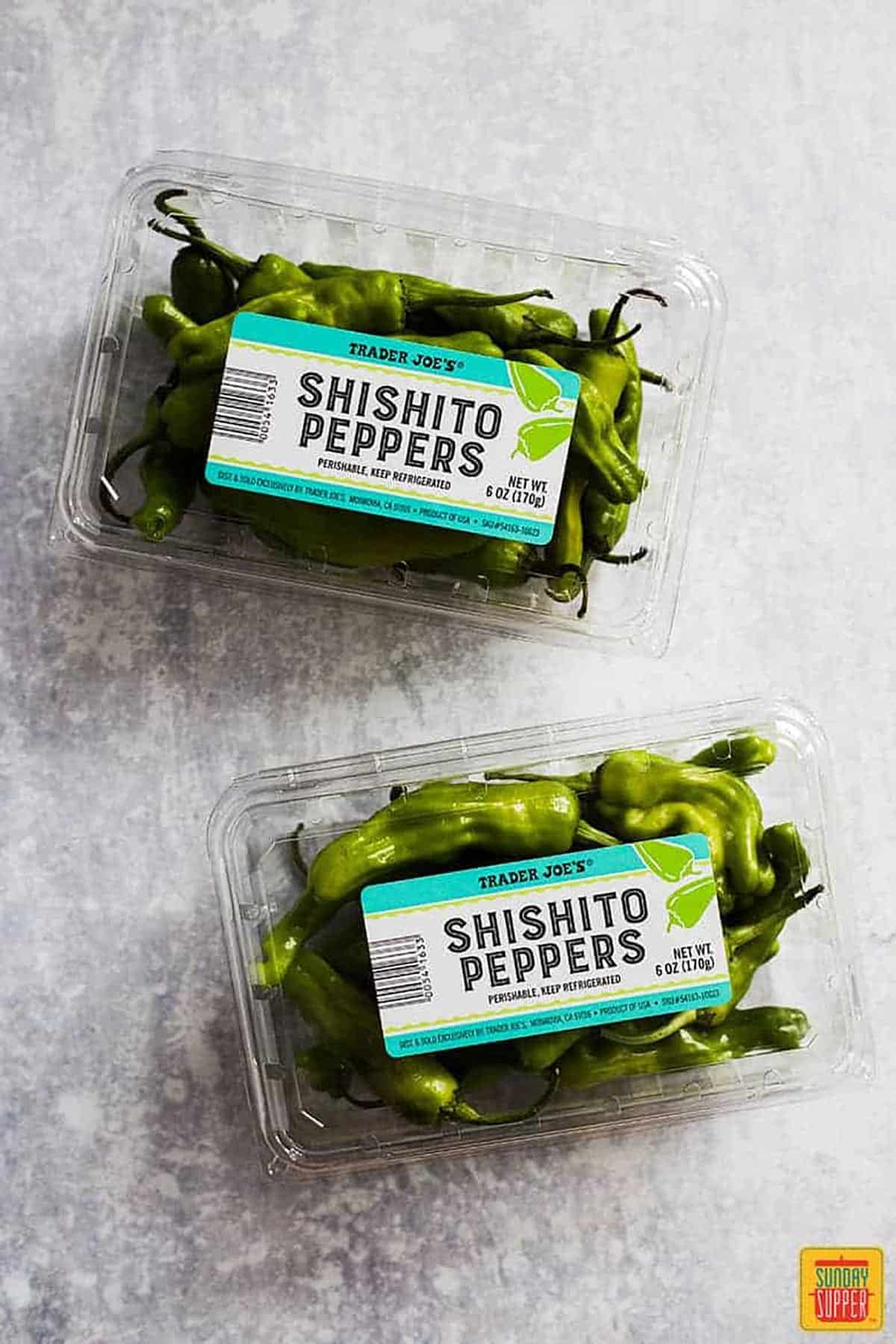 Two plastic containers of fresh shishito peppers