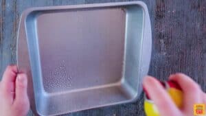 Spraying a square baking dish with cooking spray