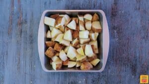 Diced potatoes in a baking tin with olive oil on top for grilled potatoes recipe