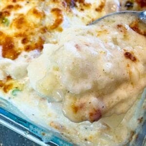 Close up of instant pot scalloped potatoes in the baking dish with a serving spoon