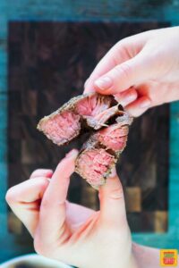 Showing the beautiful pink medium-rare of steak kebabs by splitting a piece with hands