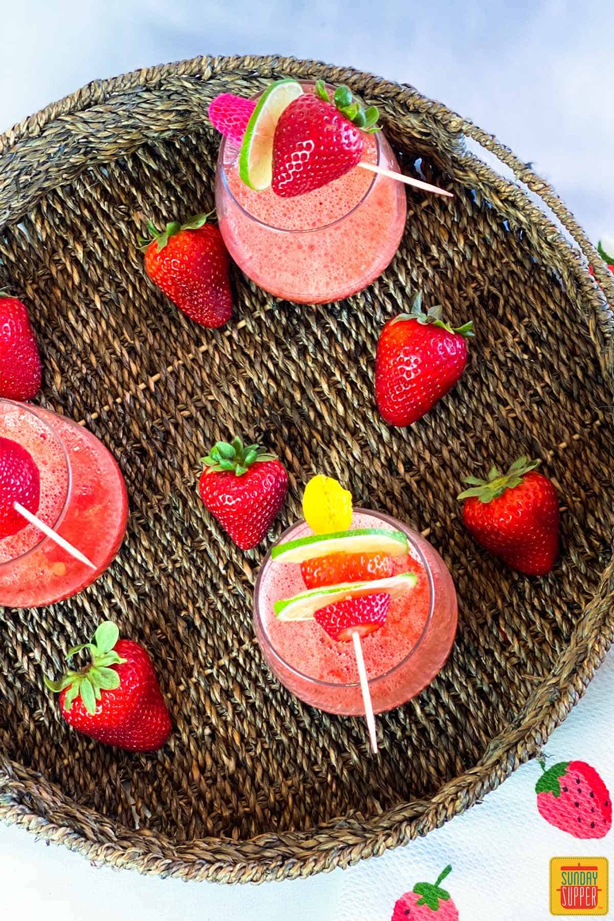 Overhead shot of three strawberry daiquiri glasses with fruit skewered on top