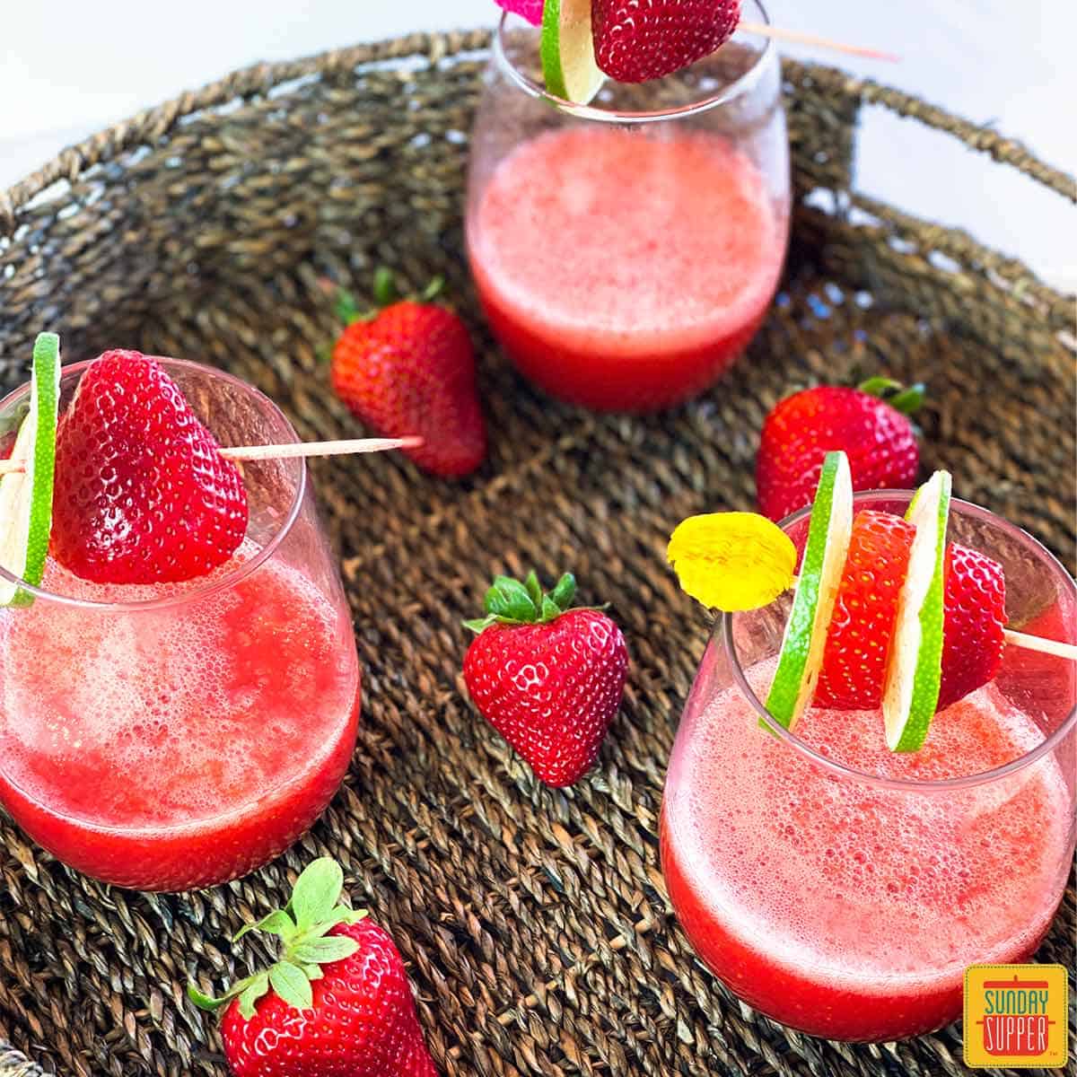 Strawberry daiquiri recipe in three glasses with fruit skewers on top