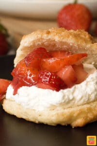 Strawberry shortcake biscuits with fresh berries and whipped cream on a black plate