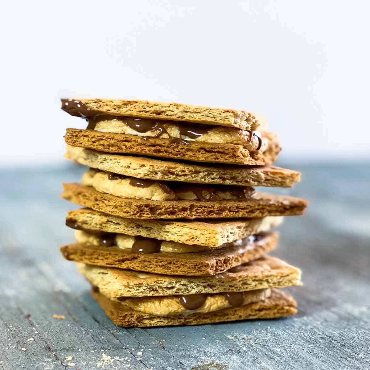 Air fryer s'mores recipe stacked on top of each other on a blue wooden surface with a white background