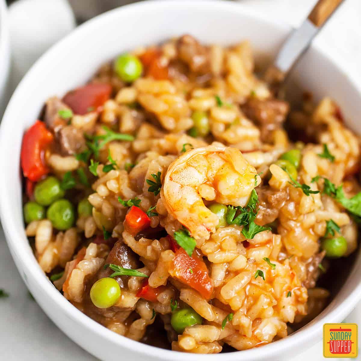 Close up of Spanish rice in a white bowl with a shrimp resting on top