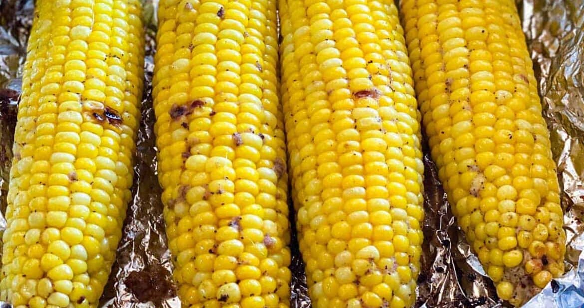 Close up of four grilled corn on the cob in a foil pack for How to Grill Corn on the Cob in Foil