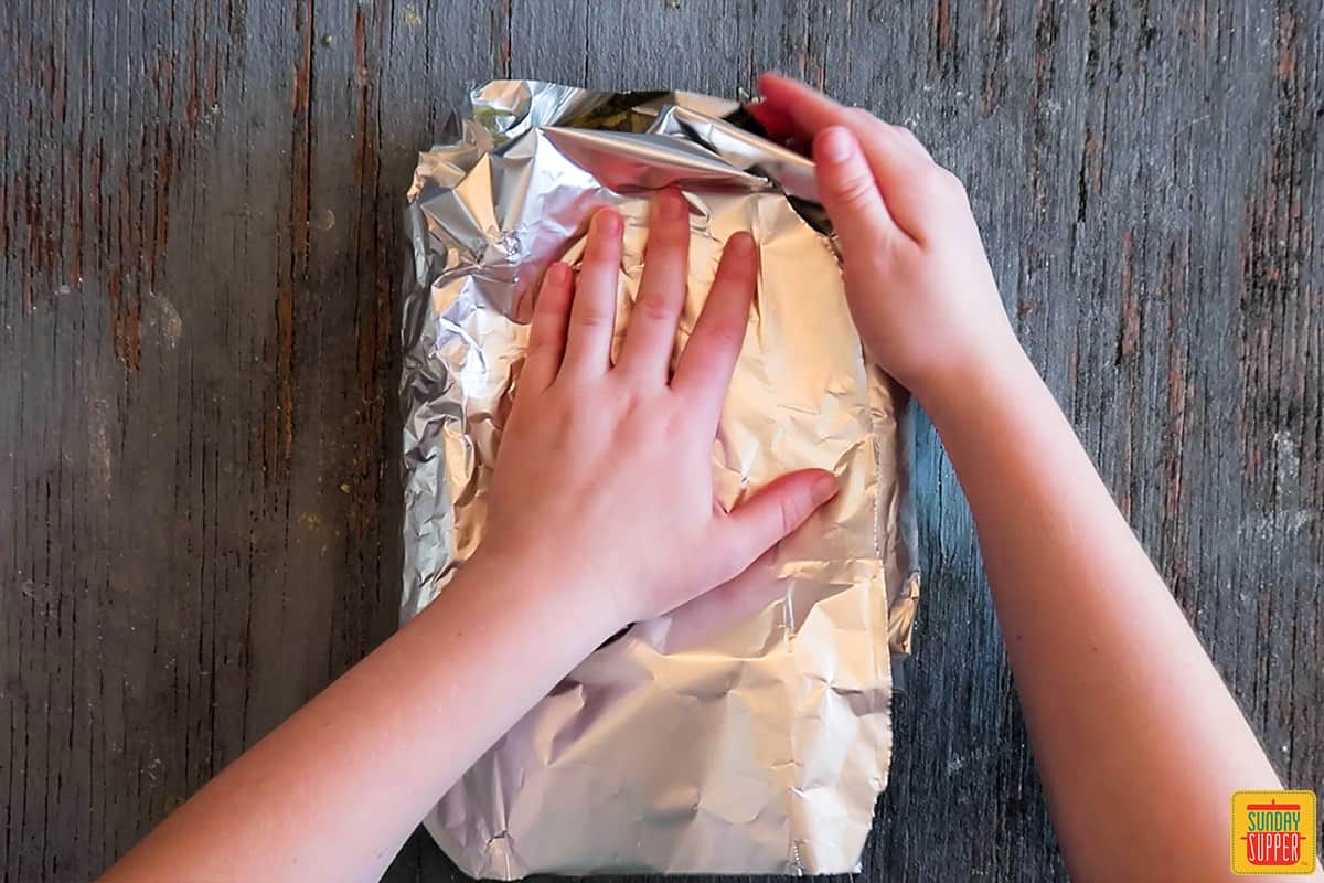 Folding the second half of foil over the corn cobs
