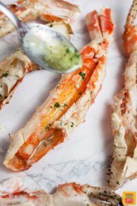 Pouring garlic butter sauce onto grilled king crab legs