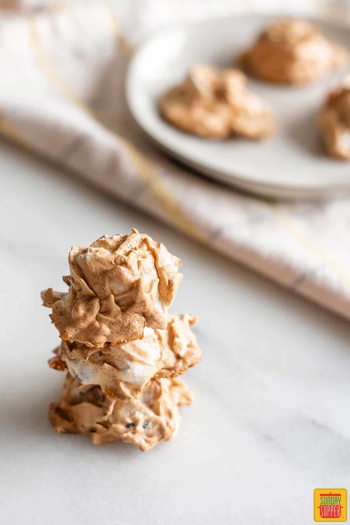 Three guava coconut cookies stacked on top of each other in front of a white plate of more cookies