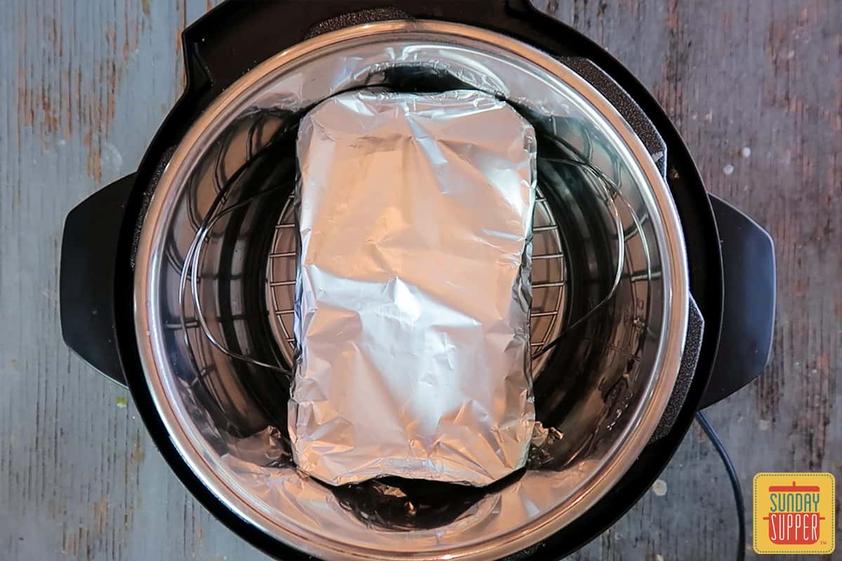 The loaf pan wrapped in foil on a trivet in the Instant Pot