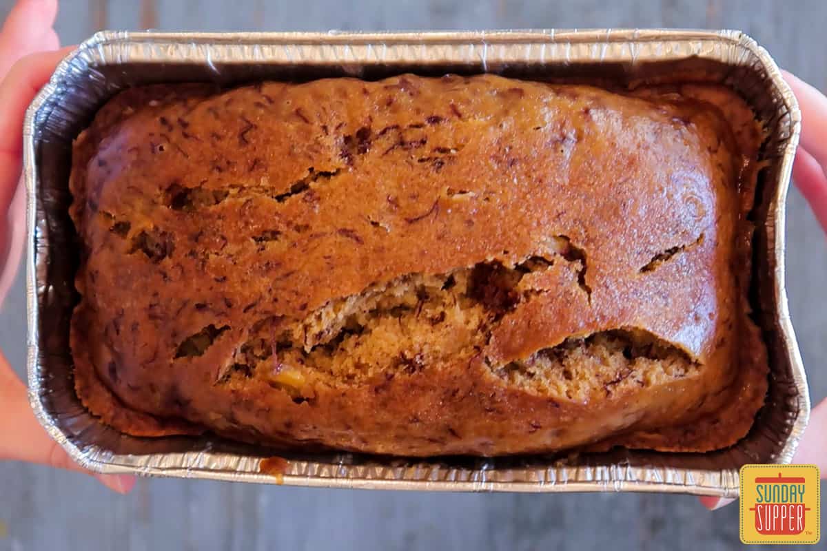 Close up of instant pot banana bread in a tin foil pan, holding with both hands