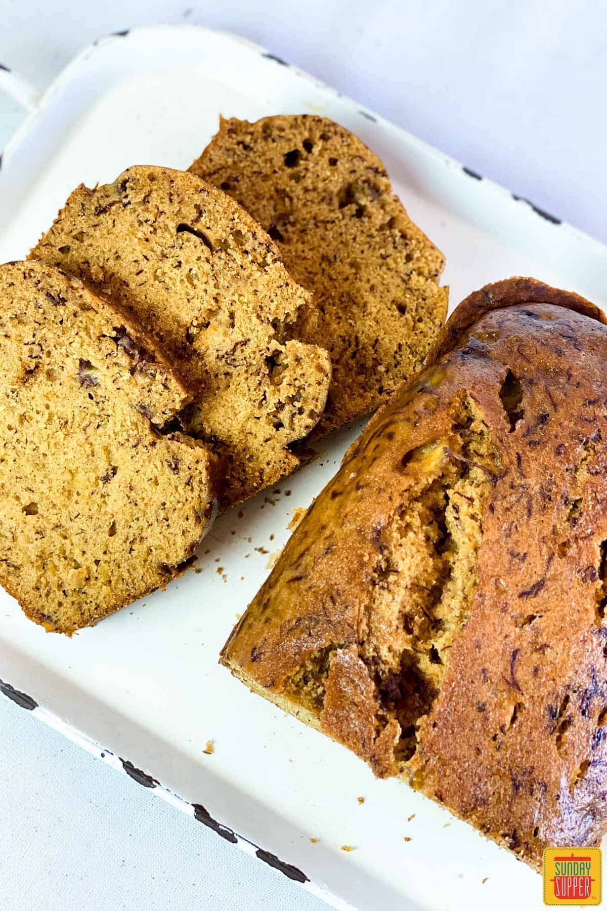 Three slices of banana bread and a loaf of Instant Pot Banana bread on a white platter
