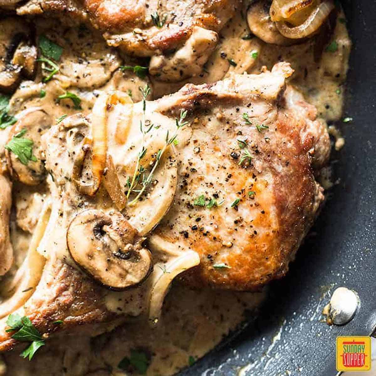 Close up on Pork Chops with Mushroom Gravy in a black skillet