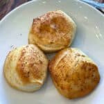 Three air fryer biscuits on a white plate up close
