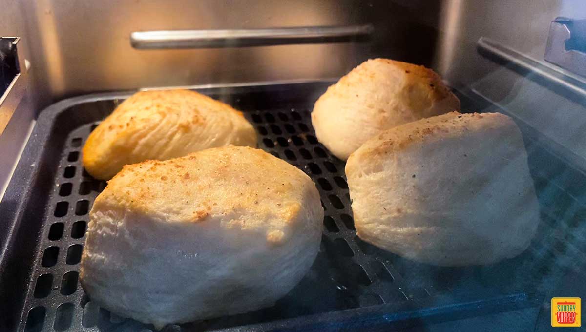 Four biscuits in the air fryer on a rack