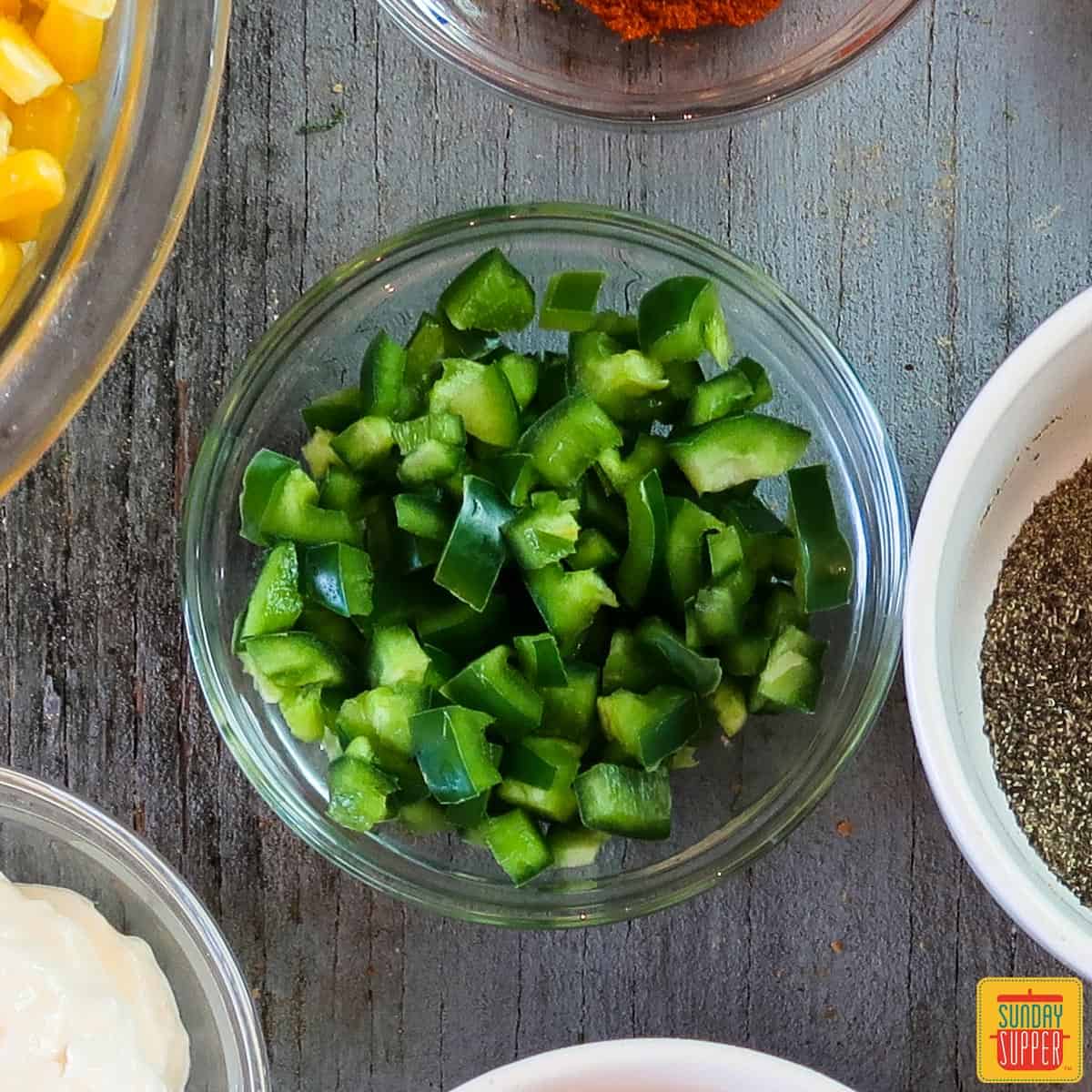 A glass bowl of diced jalapeno to show you how to cut a jalapeno