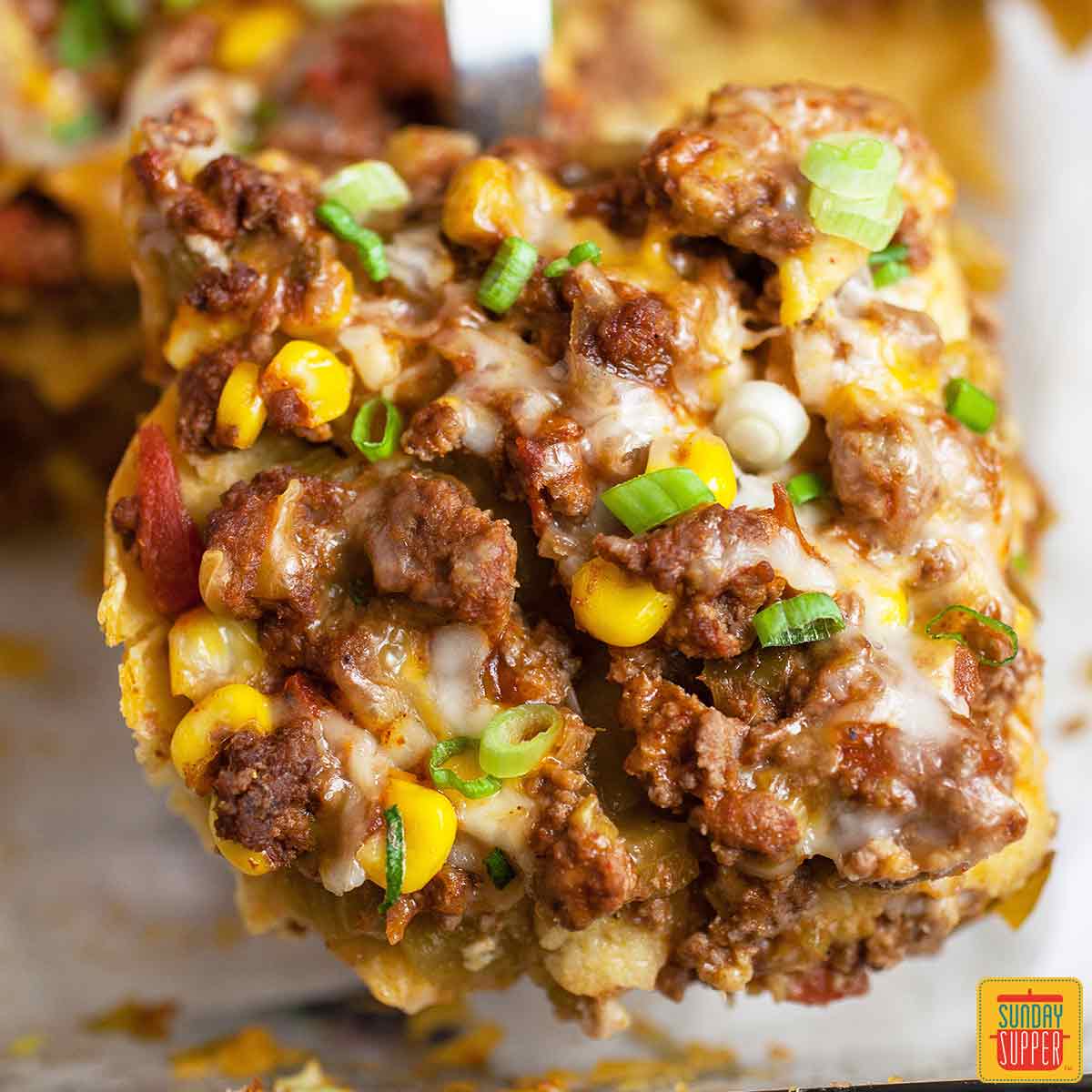 Taco lasagna on a spatula lifted out of the casserole dish