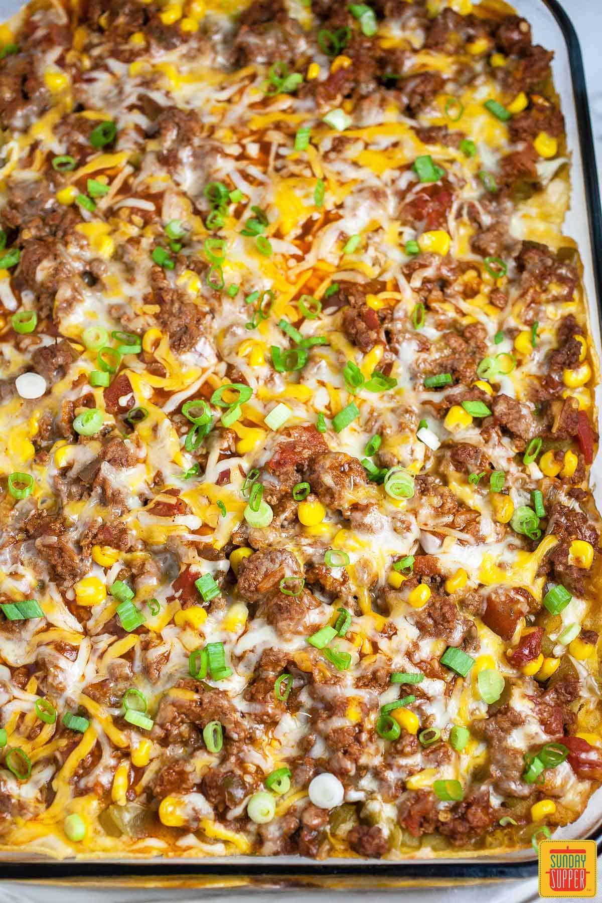 Mexican lasagna with corn tortillas in the casserole dish after baking