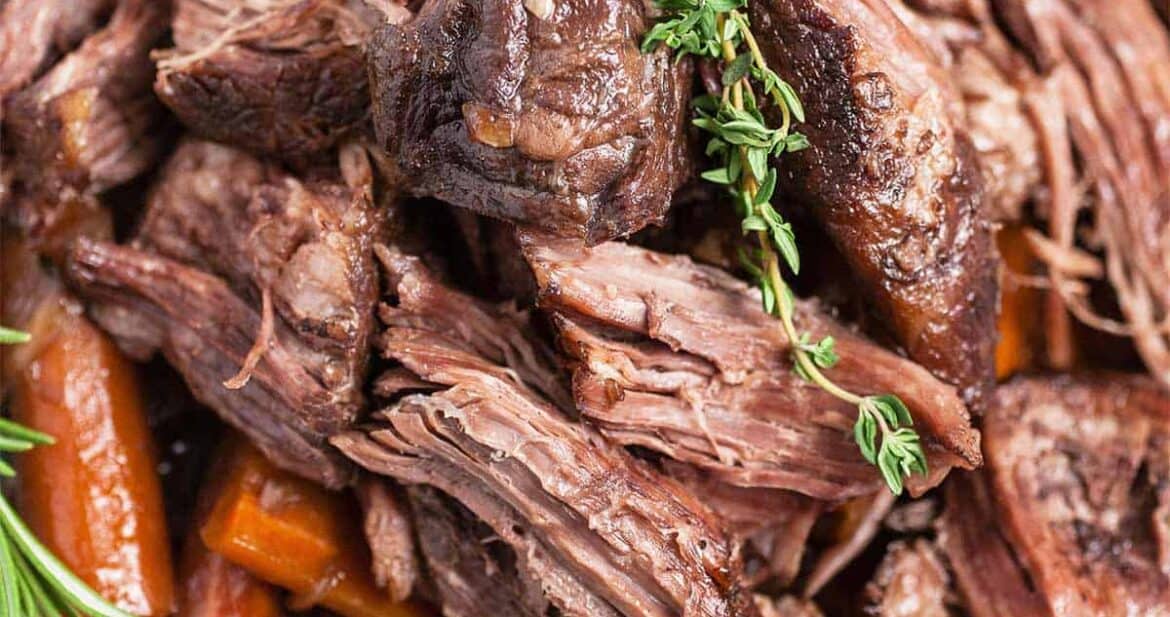 Close up of Dutch Oven pot roast meat with herbs and carrots