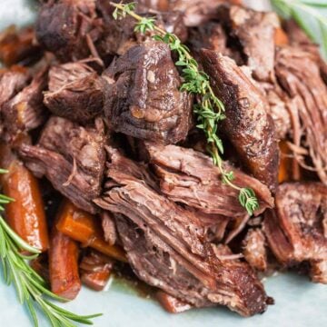 Close up of Dutch Oven pot roast meat with herbs and carrots