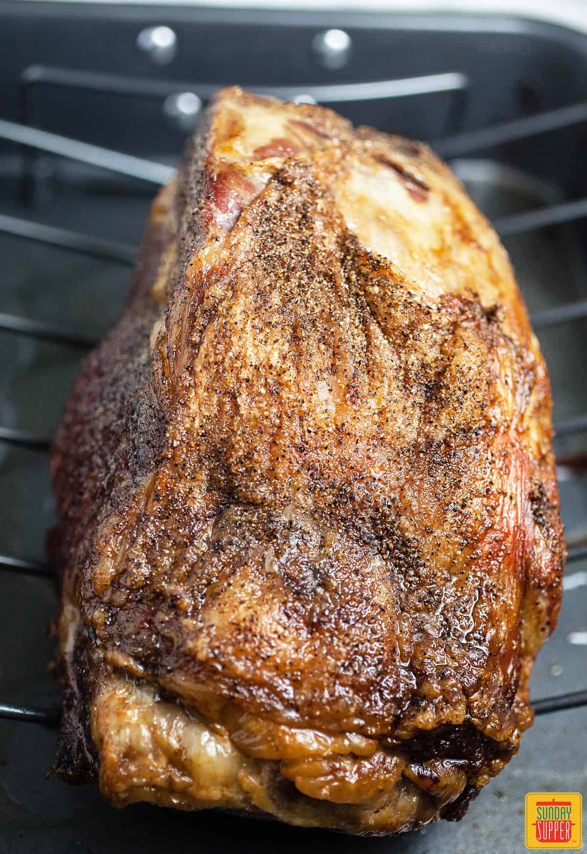 Cooked boneless prime rib roast on rack over a roasting pan