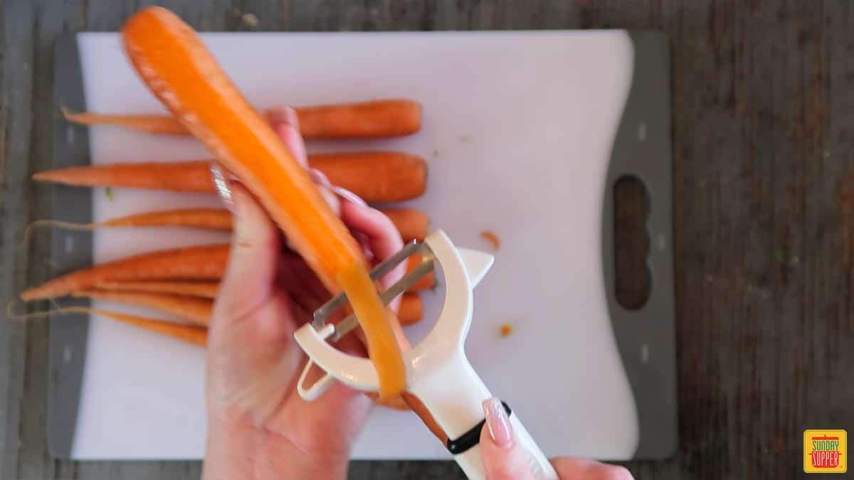 Peeling a carrot over a white cutting board