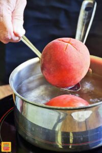 Dipping a peach into boiling water on a slotted spoon