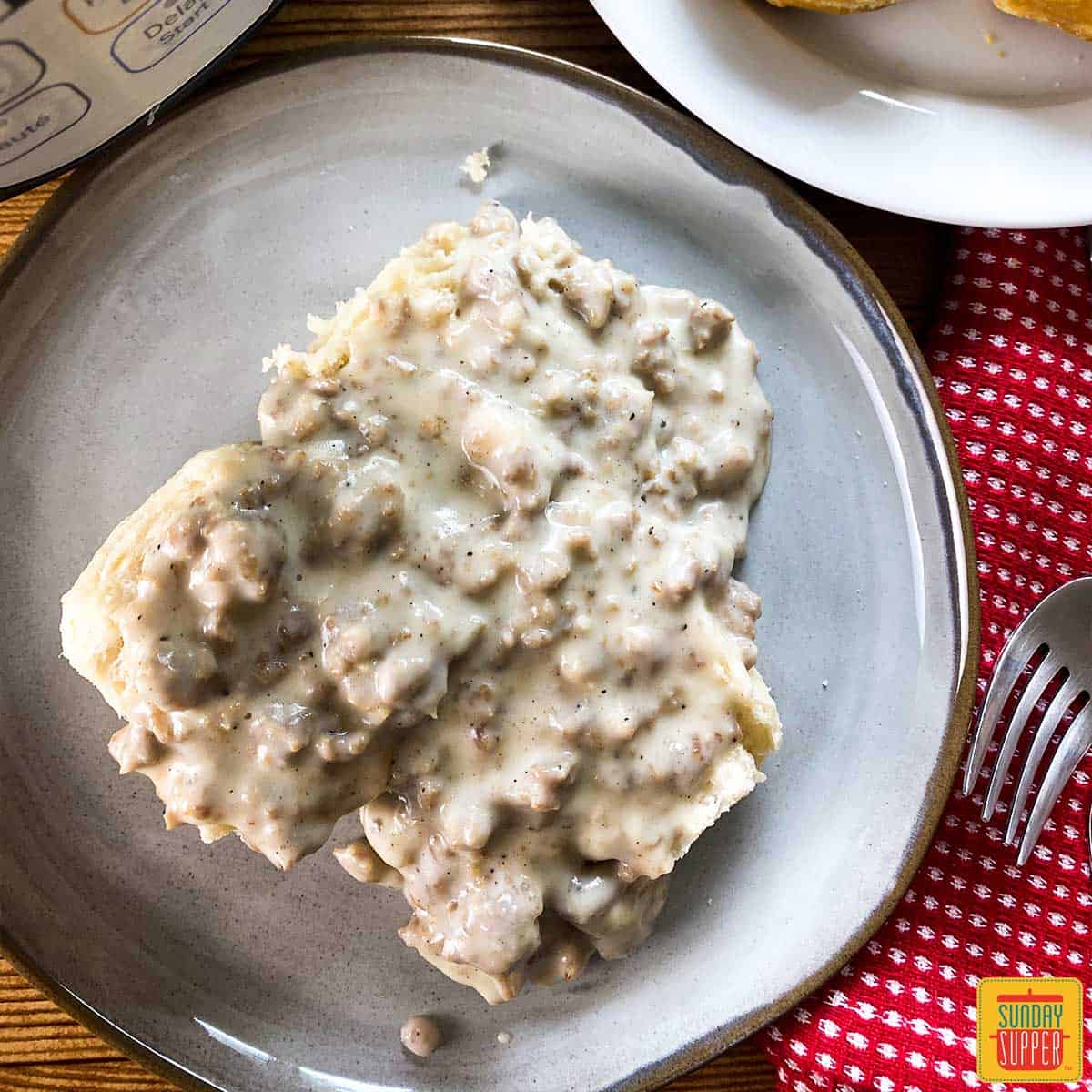 Top-down view of instant pot sausage gravy over biscuits on a plate