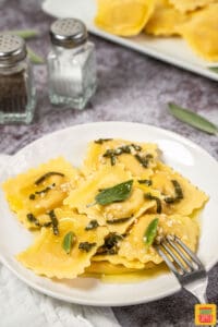 Lobster ravioli on a white plate with sage butter sauce