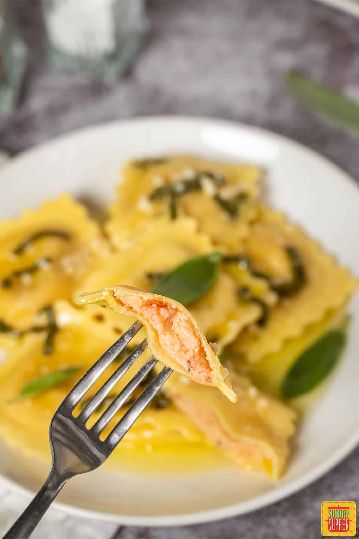 Lobster ravioli on a white plate with one on a fork