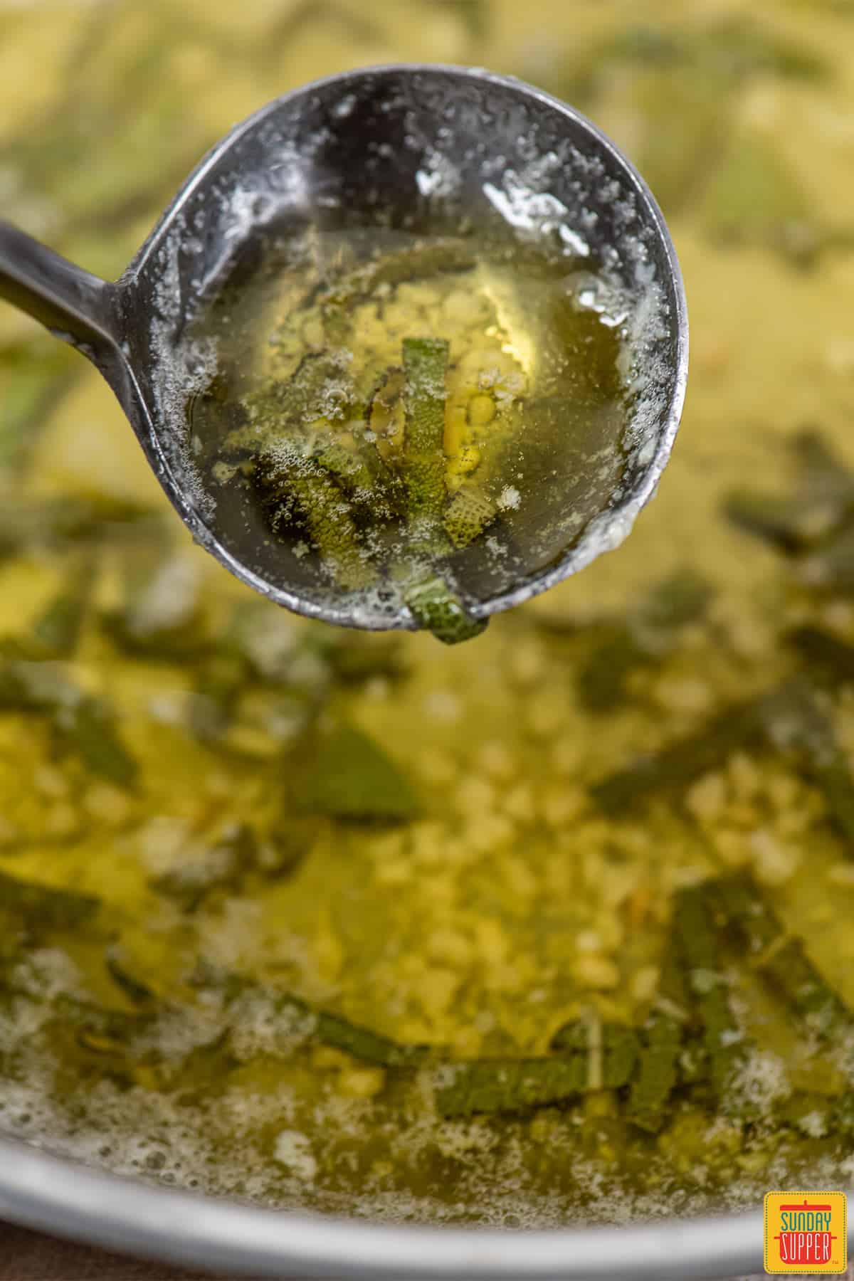 Sage butter sauce in a ladle
