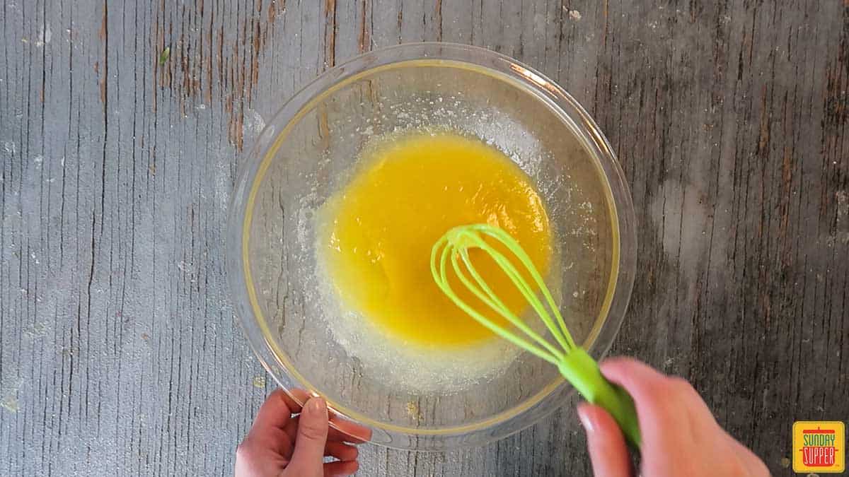 Mixing eggs into the butter and sugar with a small whisk
