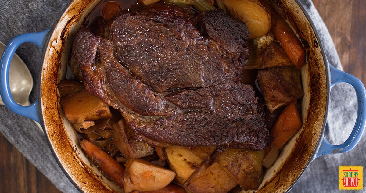 Beef chuck roast cooked over vegetables in the dutch oven
