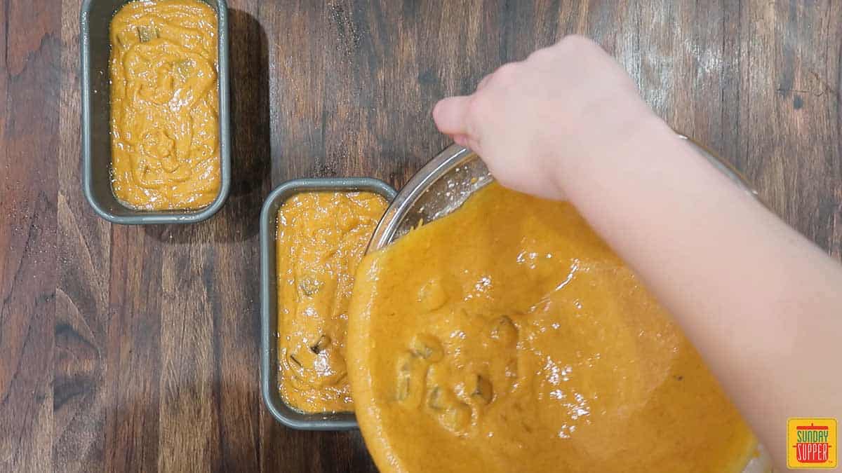 pouring chocolate chip pumpkin batter into two loaf pans