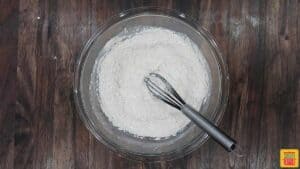 Dry flour mix to make pumpkin bread in a glass bowl with a whisk