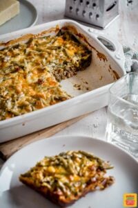 Easy cheeseburger casserole in a white casserole dish next to a plate with a single serving