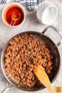 Ground beef mixed with tomato sauce and seasoning in a skillet