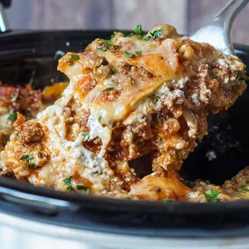 Lifting slow cooker lasagna out of the crockpot with a serving spoon