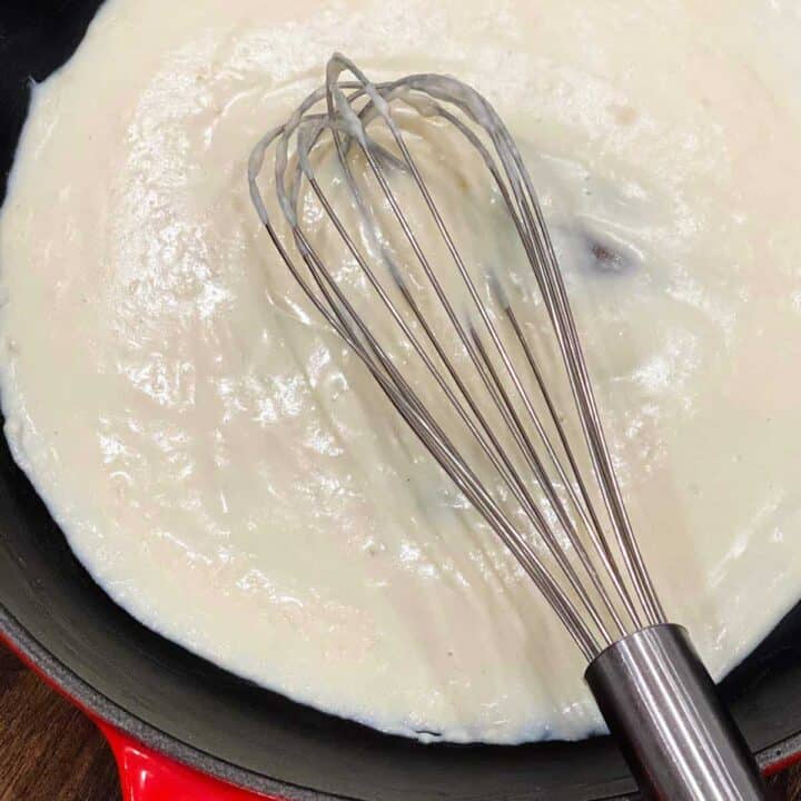 Close up of completed bechamel sauce with a whisk in a skillet