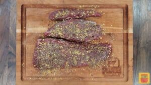 Raw beef tenderloin coated with rosemary sea salt mixture on a cutting board