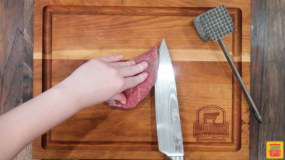 Running the knife through the center of the steak while holding it on the cutting board