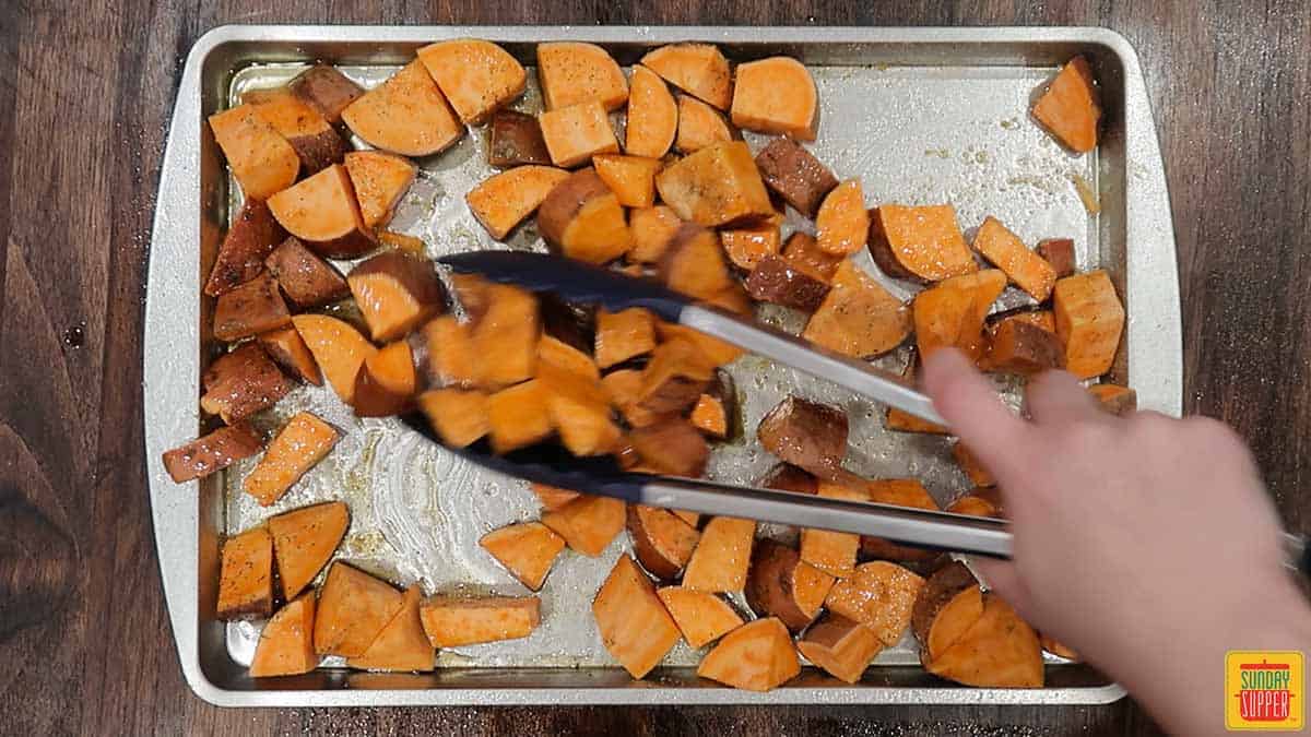 Tossing sweet potatoes with seasoning using tongs